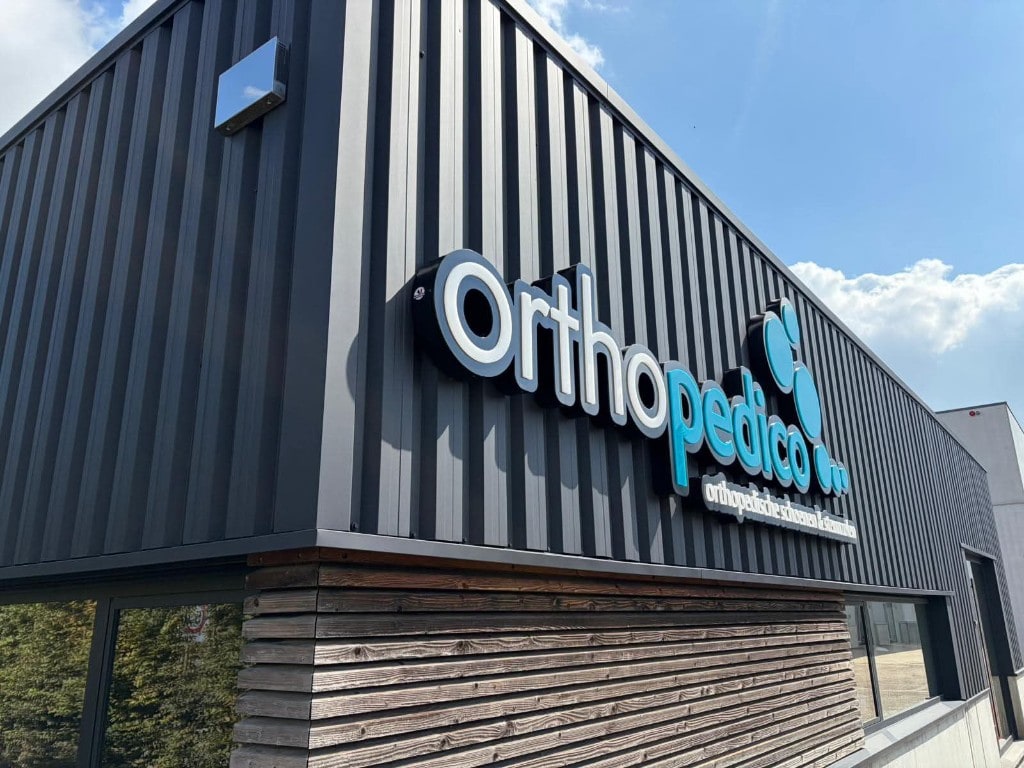 Hoekaanzicht van de zwart gespoten staalplaatgevel bij Orthopedico Sint-Truiden — strak streeploos resultaat door Fresh Decor