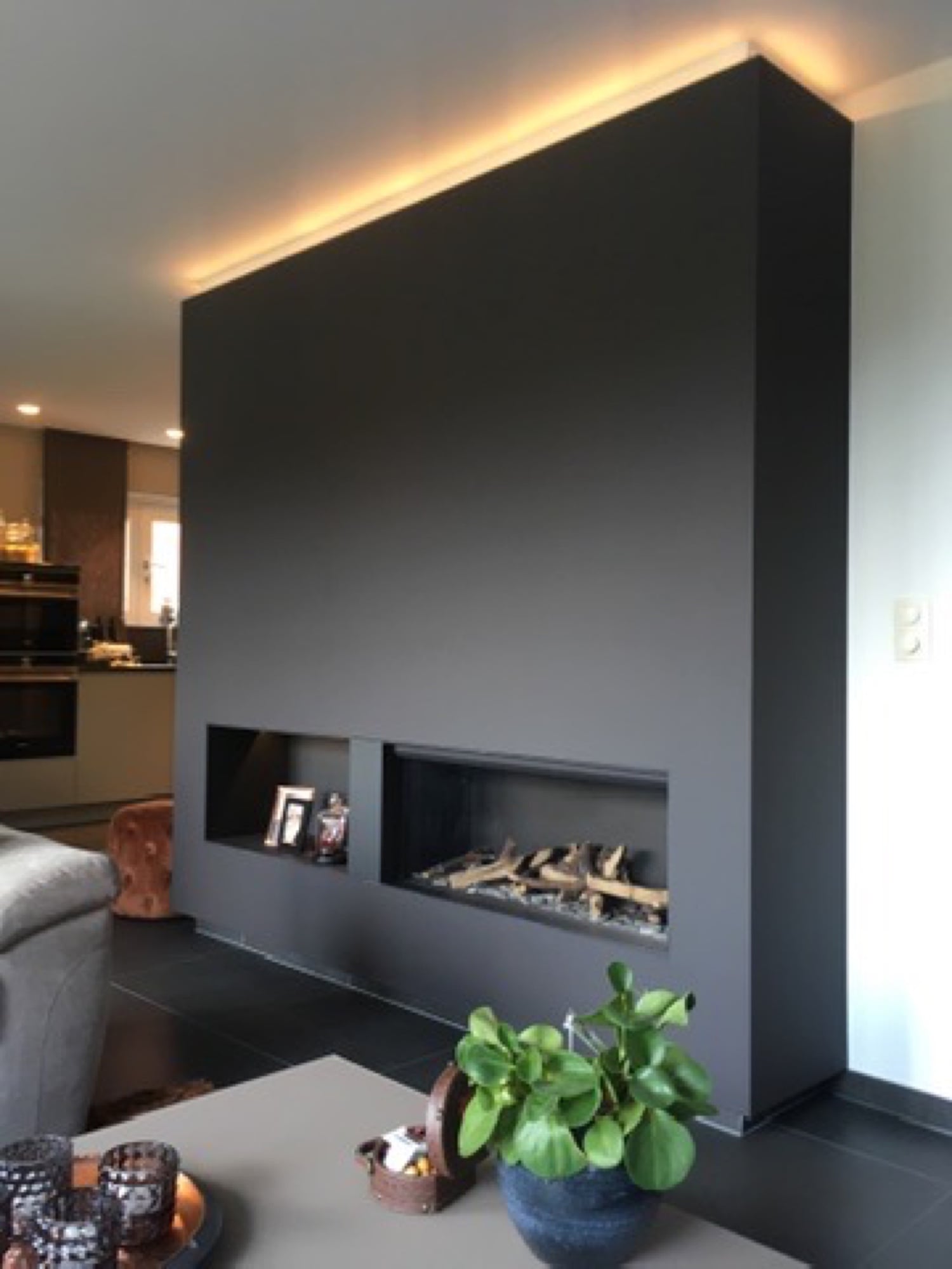 Zwarte accentwand met gashaard en LED-verlichtingsrail in een moderne living — binnenschilderwerken door Fresh Decor Limburg