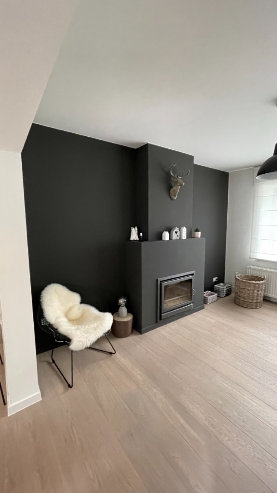Zwarte accentwand met haard en open haard in een moderne living — binnenschilderwerken door Fresh Decor Limburg