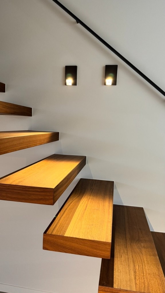 Witte wand & trapverlichting Strak wit binnenschilderwerk bij een houten trap met sobere wandarmaturen — Fresh Decor vakmanschap Limburg
