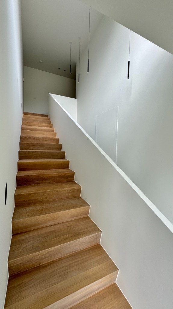 Trap met hanglampen Moderne houten trap met wit geschilderde borstwering en design hanglampen — interieurschilderwerk Fresh Decor Limburg