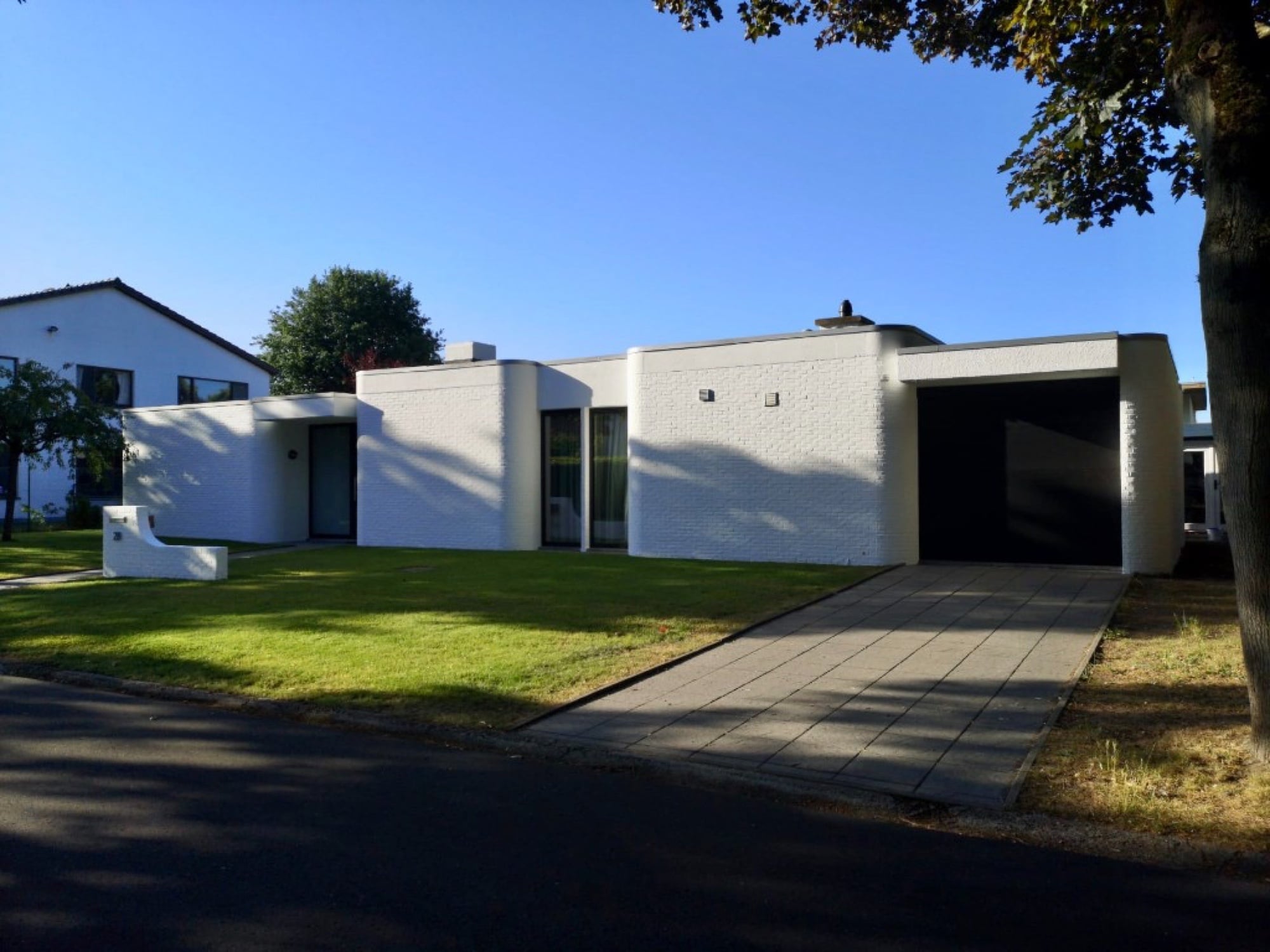 Moderne woning met strak wit geschilderde bakstenen gevel en garage — buitenschilderwerk en gevelafwerking door Fresh Decor in Limburg