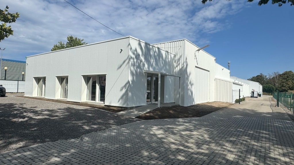 Bedrijfsgebouw Comed in Bilzen-Hoeselt met wit airless gespoten profielplaatgevel en kantoorvleugel — spuitwerken door Fresh Decor
