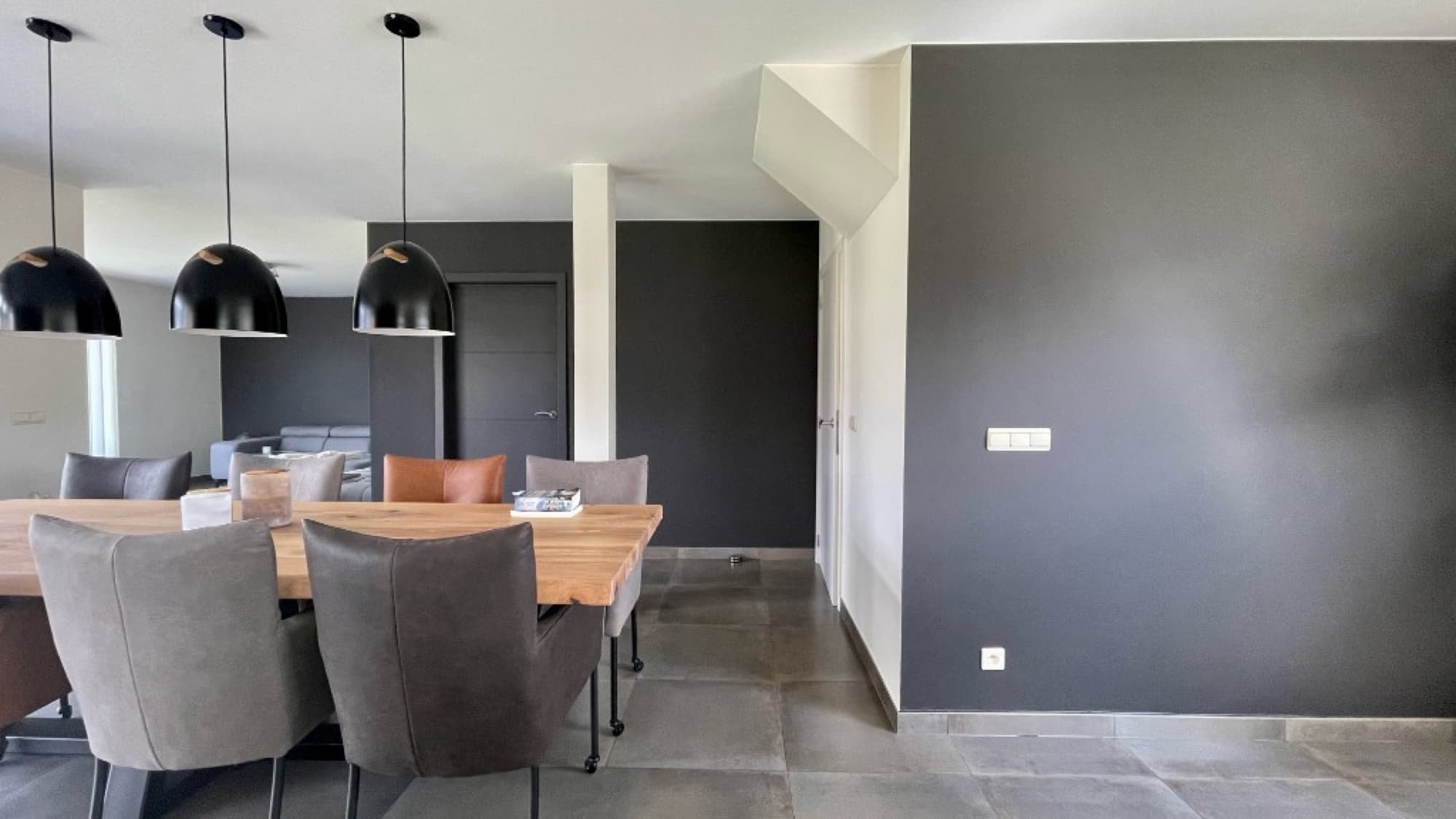 Moderne eetkamer met antraciet geschilderde wanden, zwarte hanglampen en houten eettafel — binnenschilderwerken door Fresh Decor Limburg