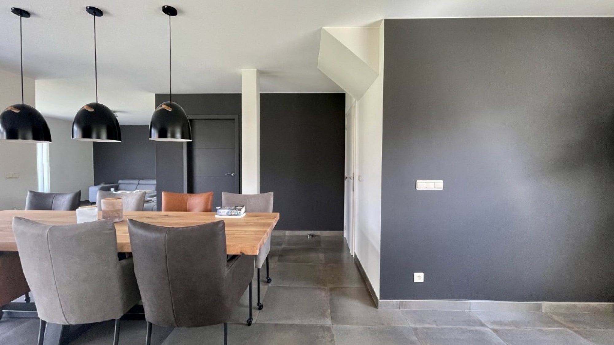 Moderne eetkamer met antraciet geschilderde wanden, zwarte hanglampen en houten eettafel — binnenschilderwerken door Fresh Decor Limburg