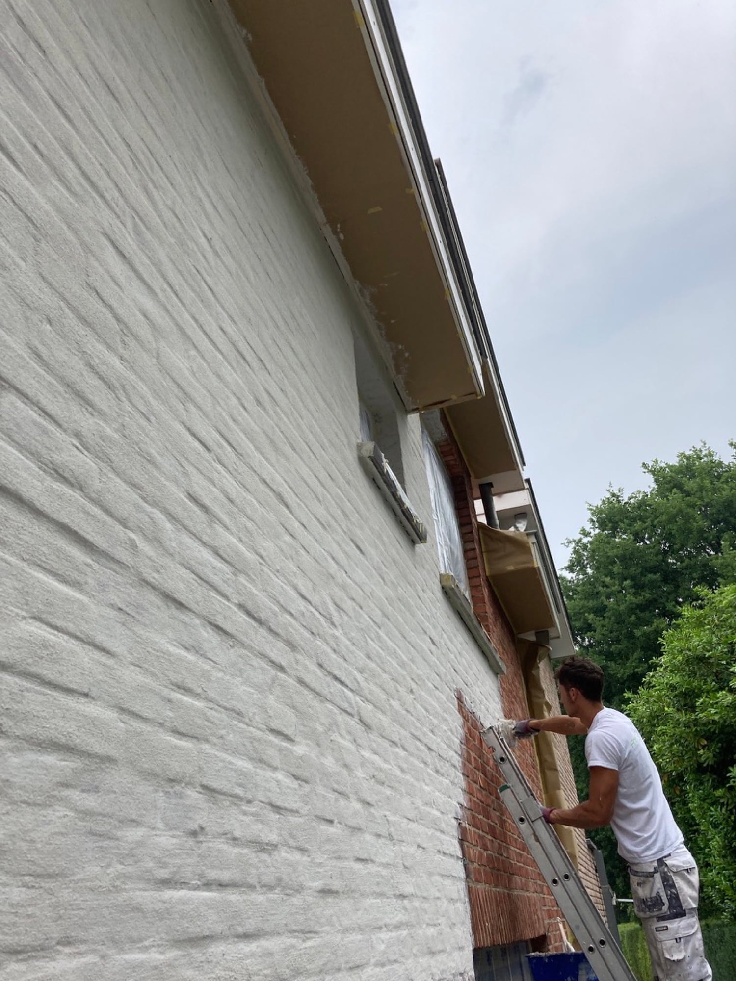 Vakman van Fresh Decor kaleiert een bakstenen gevel op ladder — gevel kaleien Limburg