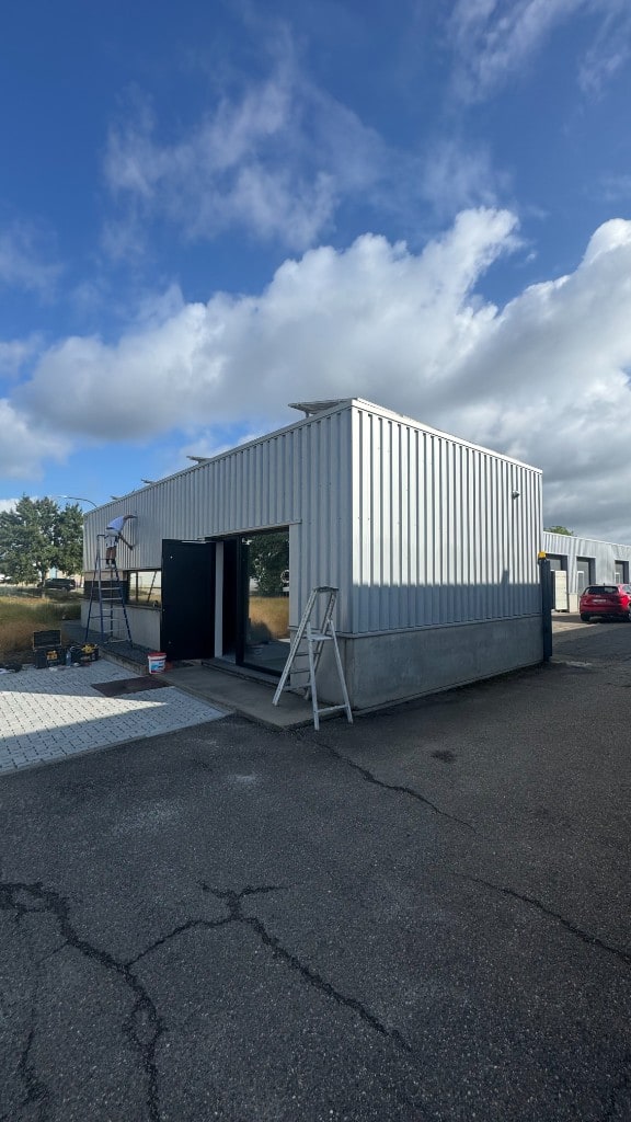 Voor de werken: de witte profielplaatgevel van Orthopedico in Sint-Truiden, klaar om zwart gespoten te worden door Fresh Decor