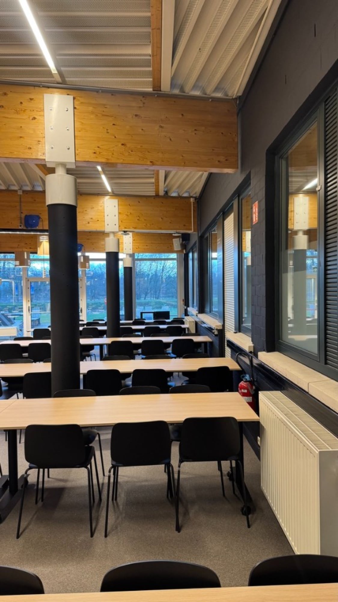 Geschilderd klaslokaal PXL Hogeschool Hasselt — zwarte kolommen en wanden, houten plafond — zakelijke schilderwerken Fresh Decor Limburg